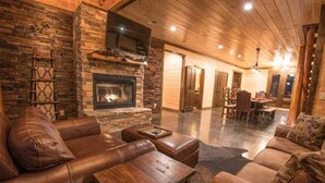 A cozy living room with a stone fireplace, leather sofas, and wooden tables.