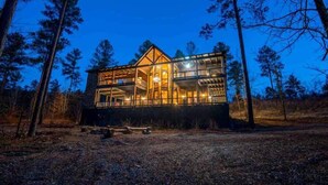 A cabin with a glass facade, surrounded by trees.