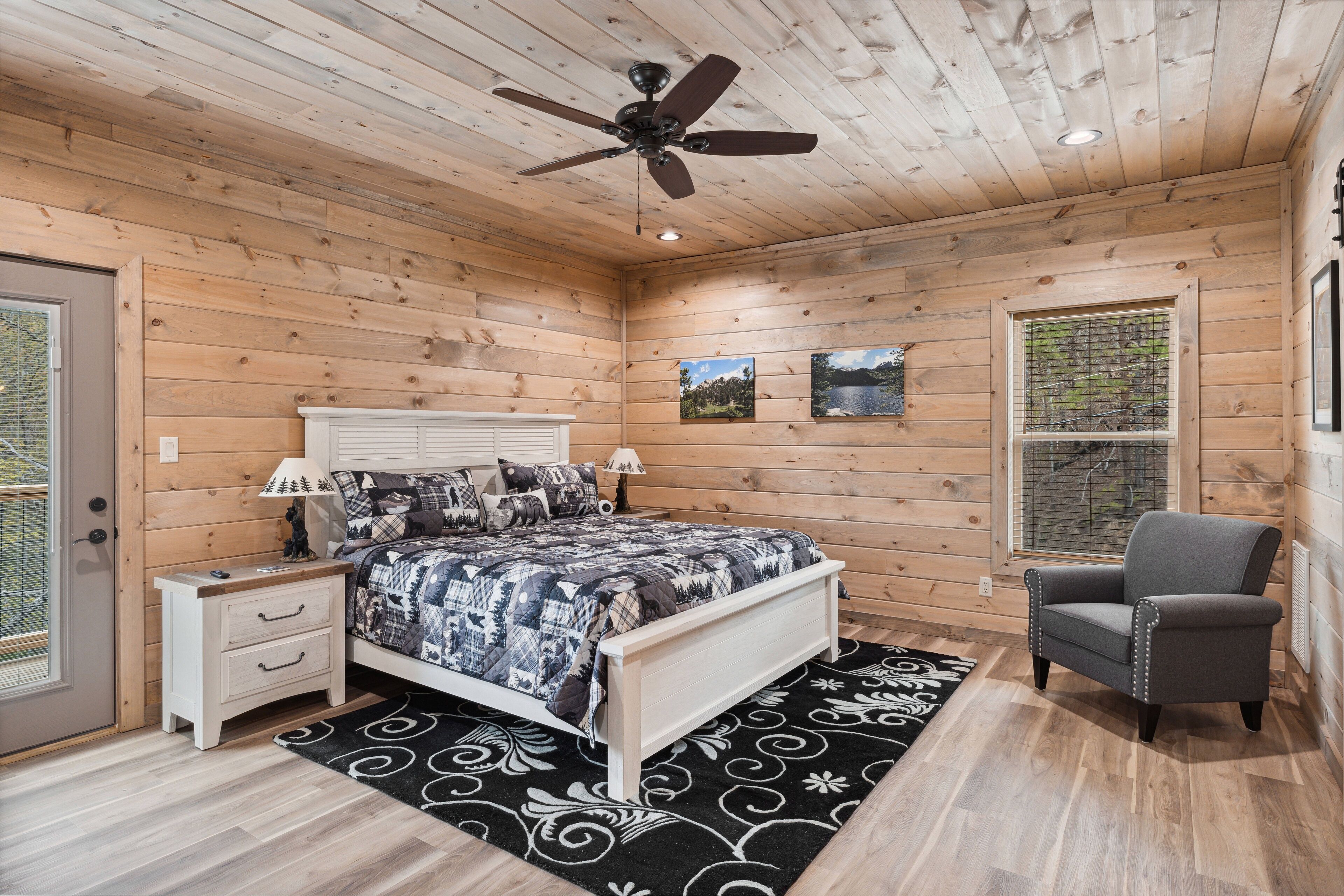 Een slaapkamer met een bed, nachtkastjes, een stoel, een plafondventilator en een raam met uitzicht.