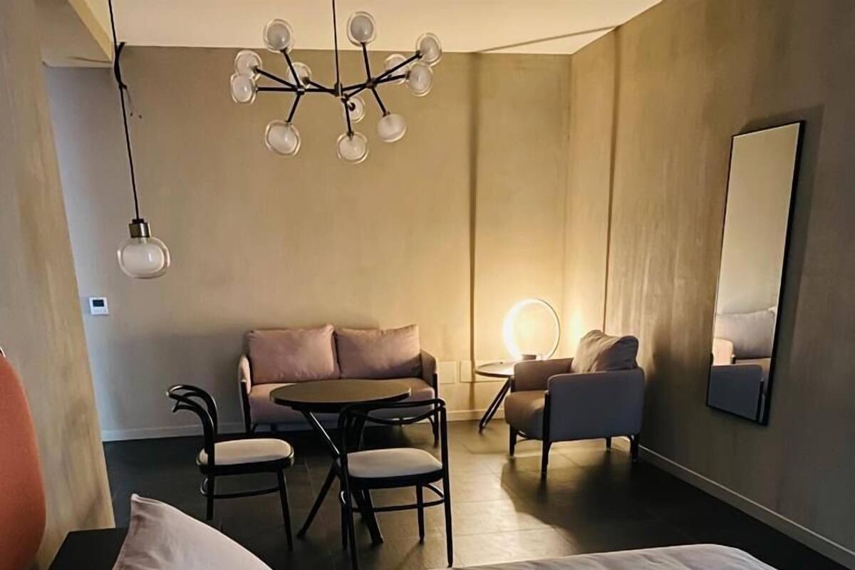 A hotel room with a bed, a desk, a sofa, and a chair.