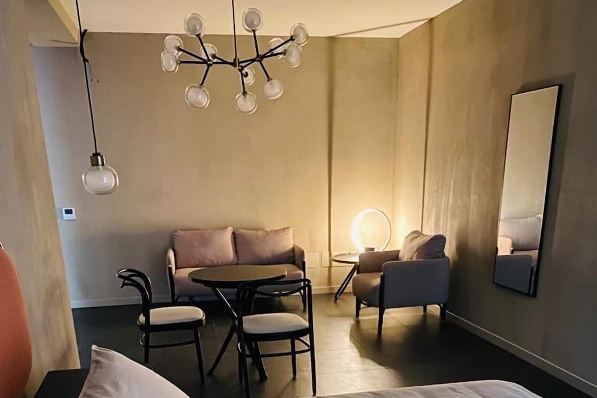 A hotel room with a bed, a desk, a sofa, and a chair.