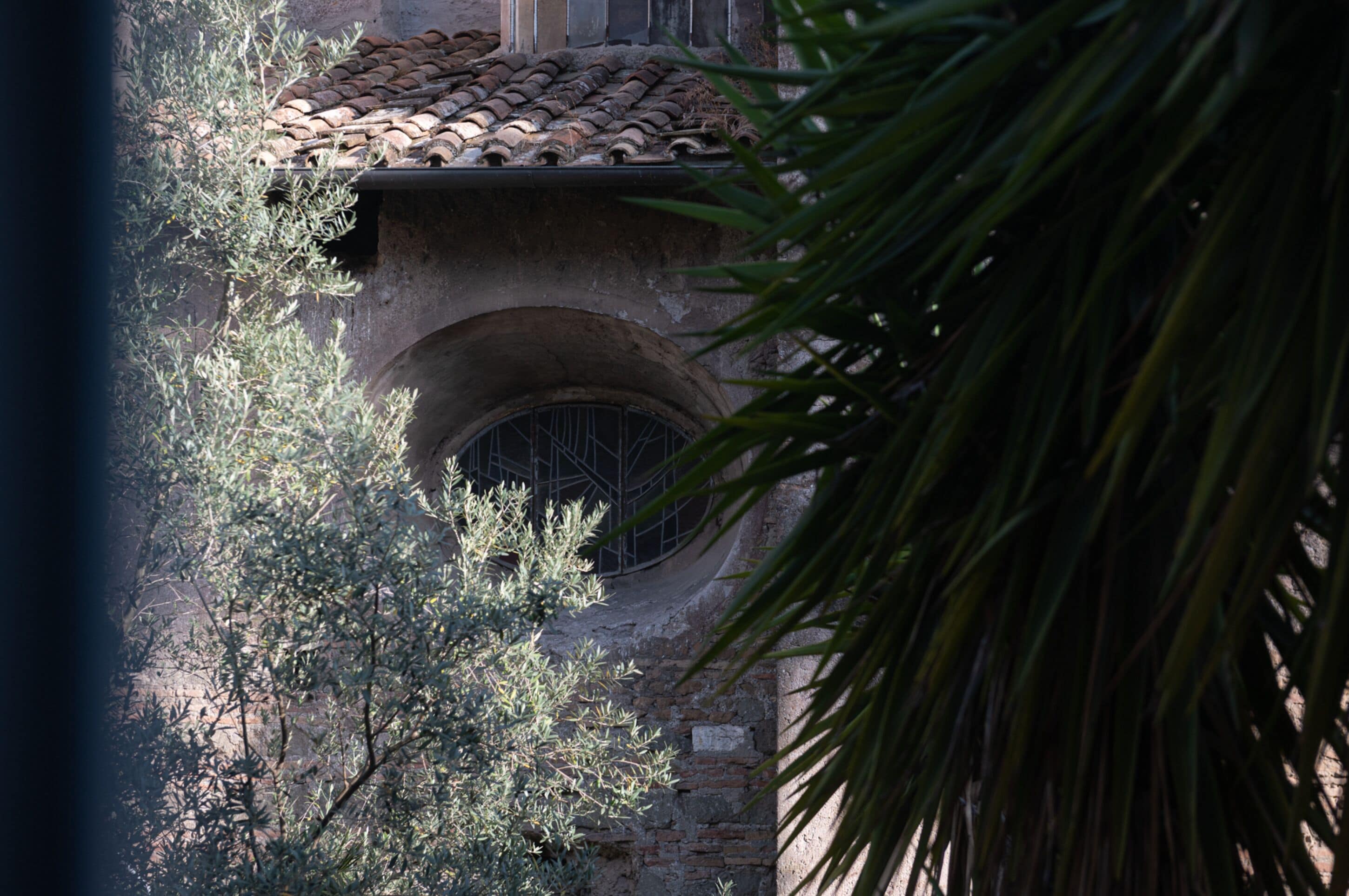 A stone building with a tiled roof and a circular window.