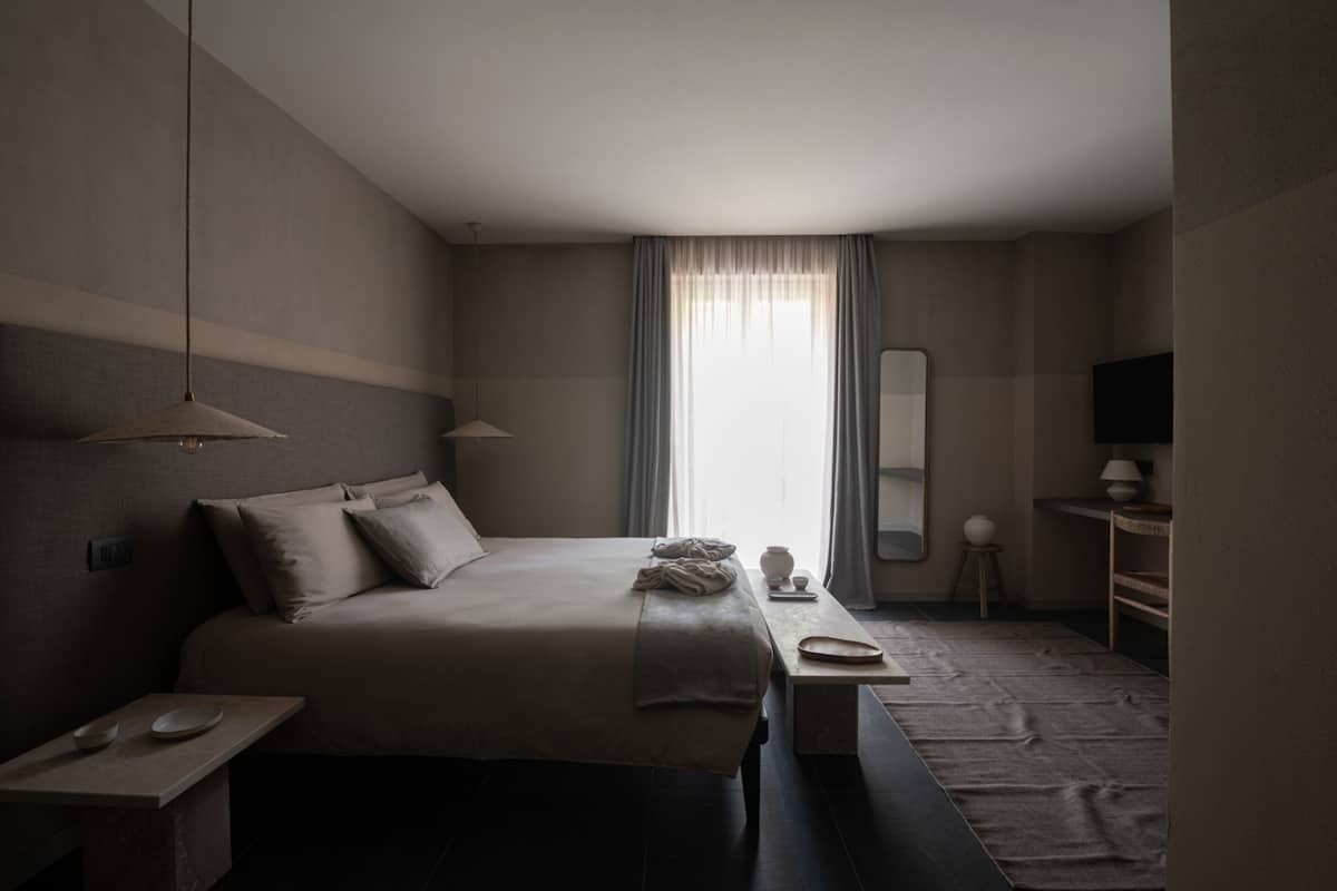 A modern hotel room with a large bed, bedside table, and a television.