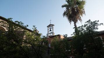 A church with a bell tower, surrounded by trees and buildings.
