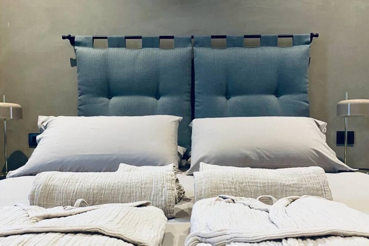 A double bed with two pillows, a headboard, and two bedside lamps.