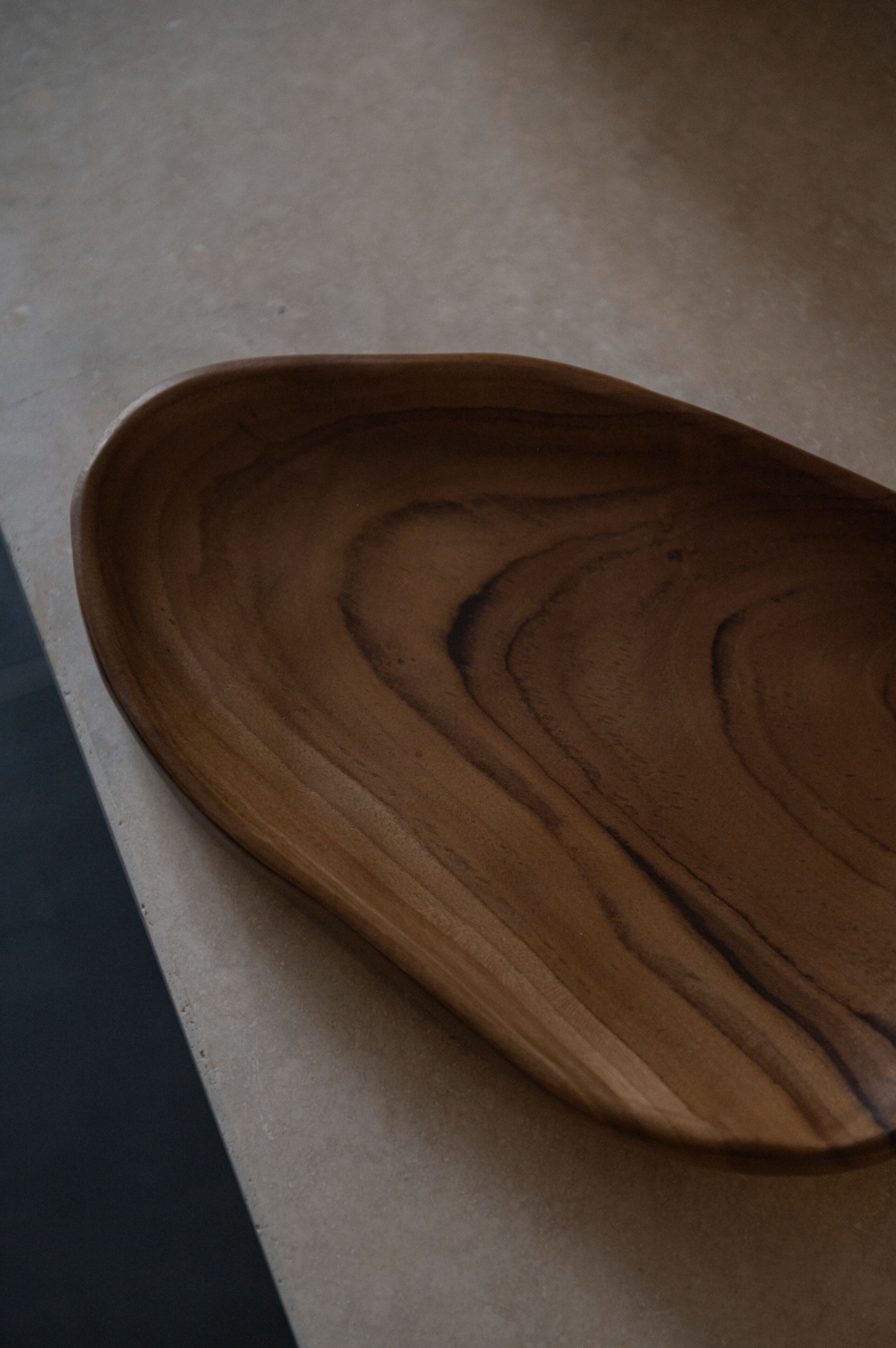Un plateau en bois, doté d’un bord lisse et incurvé, posé sur une surface plane.