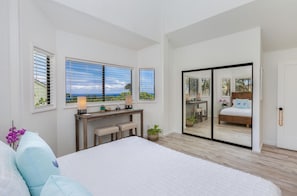 Une chambre avec un grand lit, un bureau et une porte-fenêtre coulissante donnant sur un balcon.