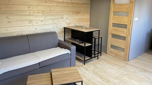 Ein modernes Interieur mit einem grauen Sofa, Holzregalen und einer Schiebetür.
