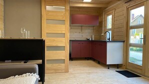 Eine kleine Küche mit Holzwänden, einem eingebauten Spülbecken und einem Fenster mit Blick hinaus.