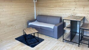 Ein gemütliches Zimmer mit einem grauen Sofa, einem kleinen Holztisch und einem schwarzen Metalltisch.