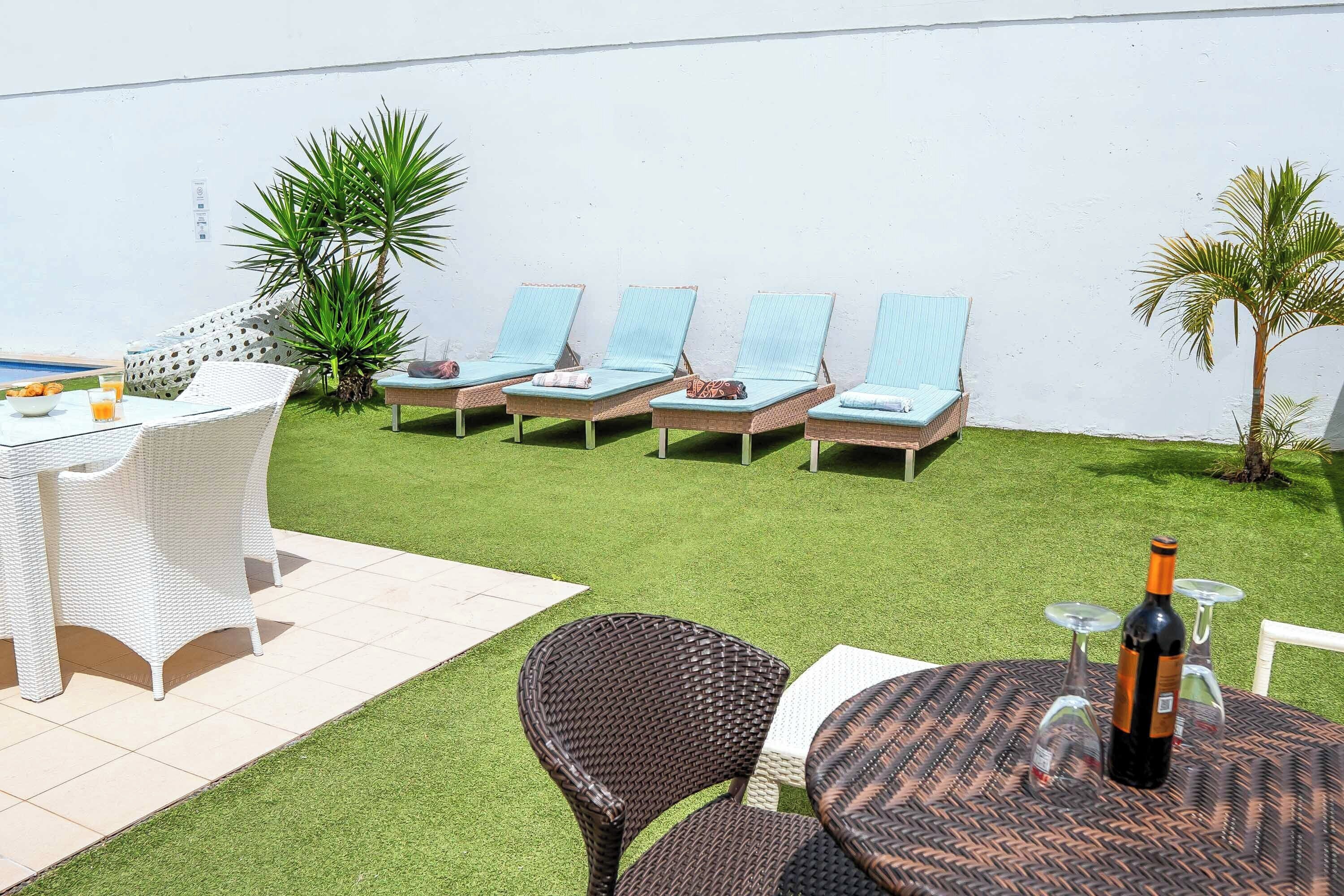 A patio area with a table, chairs, and a lounge area with sun loungers.