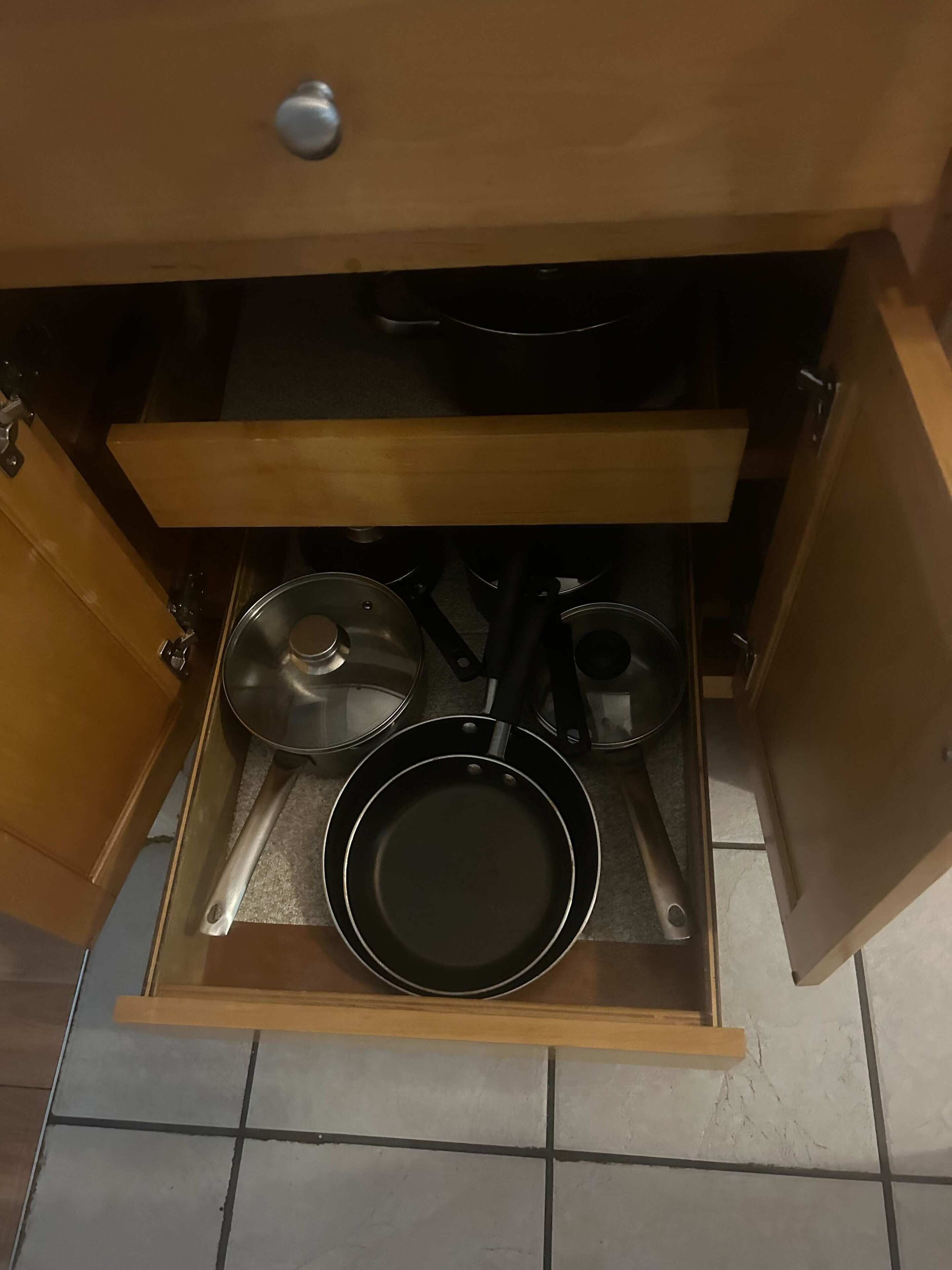 Un tiroir de cuisine contenant une poêle, une casserole et une autre poêle.