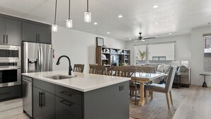 Una cucina moderna con isola centrale, elettrodomestici in acciaio inossidabile e zona pranzo con mobili in legno.