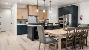 Una cucina moderna con mobili scuri, un'isola centrale e luci a sospensione.