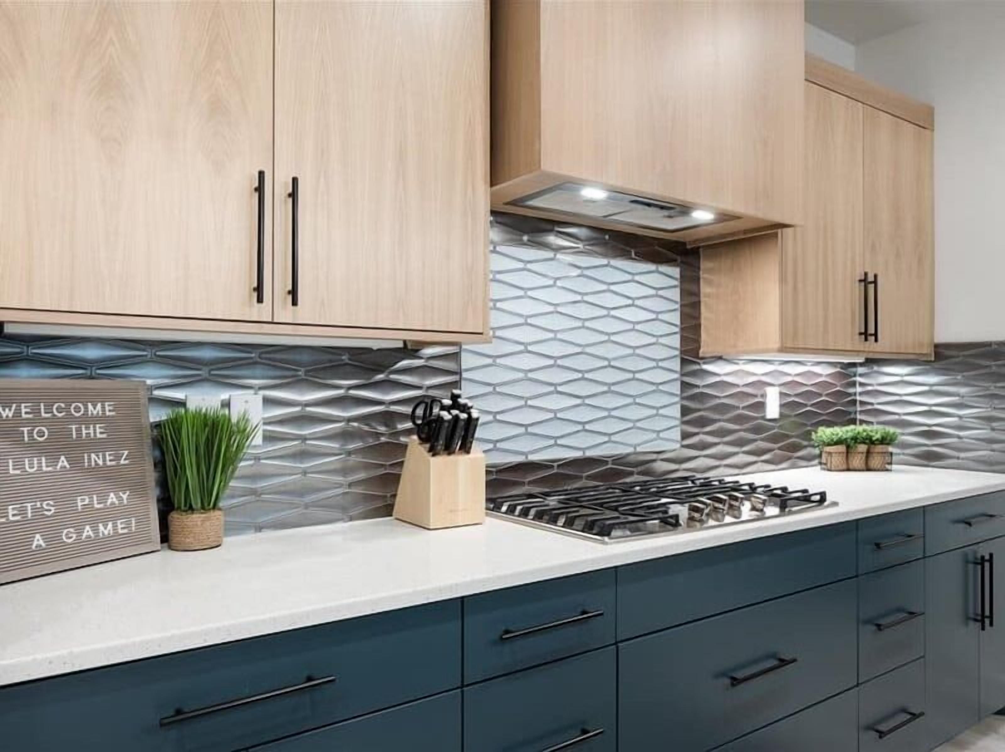 Una cocina moderna con armarios de madera, una estufa a gas y un salpicadero con un diseño geométrico.