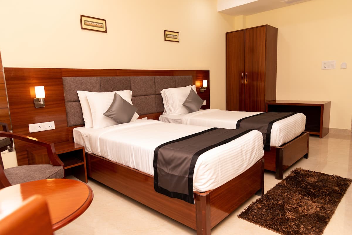 Una habitación de hotel con una cama de madera, dos mesitas de noche, una silla, un armario y una pequeña alfombra.