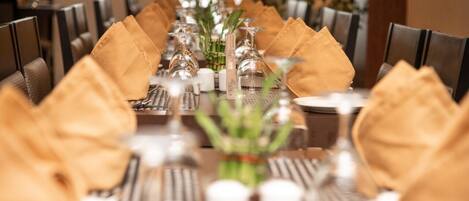A dining table set with gold napkins, clear glassware, and white candles.
