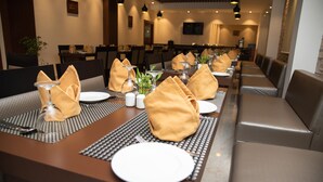 Een restaurant met een lange eettafel, voorzien van borden, servetten en bestek.