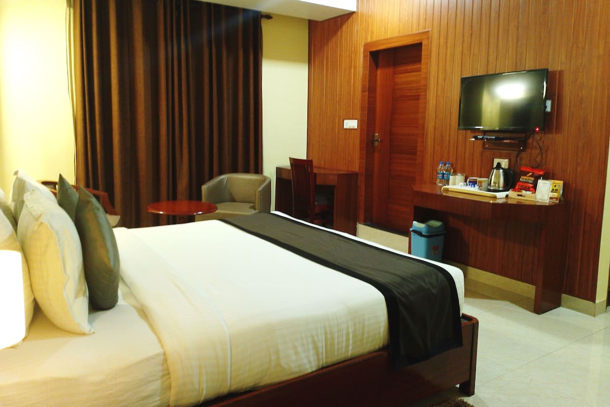 Una habitación de hotel con cama, televisión, escritorio y una silla.