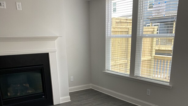 A room with a fireplace, large windows, and a grey wooden floor. - Town house for rent (Lilburn)