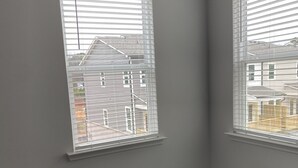 A room with two windows, carpeted floor, and a visible electrical outlet. - Town house for rent (Lilburn)