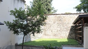 A courtyard with a stone wall, a potted tree, and a small patch of grass. - Apartment that sleeps 4 a stone's throw from Parma Cathedral (Parma)