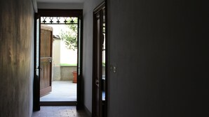 A hallway leading to a door with a metal gate, a potted plant, and a concrete floor. - Apartment that sleeps 4 a stone's throw from Parma Cathedral (Parma)