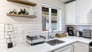 Une cuisine moderne avec des meubles blancs, un évier encastré et une fenêtre qui laisse entrer la lumière naturelle.