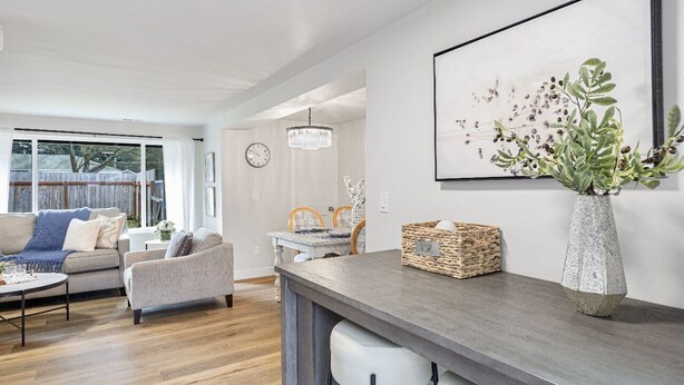 Un salon moderne comprenant un canapé, des fauteuils, une table basse et un coin repas agrémenté d’un lustre.