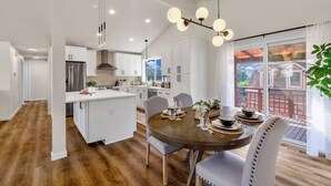 Een moderne keuken met witte kasten, een centraal eiland en een eethoek met een ronde tafel en stoelen.