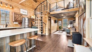 Une cabane spacieuse comprenant une cuisine, un coin repas et une chambre à coucher située en mezzanine.