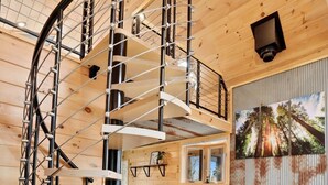 Un escalier en colimaçon avec des rampes en métal, situé dans un intérieur en bois.