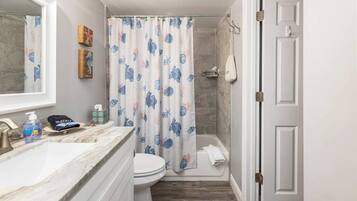 A bathroom with a shower, toilet, and sink.