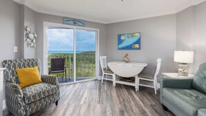 A room with a dining table, two chairs, a sofa, and a view of the ocean. - Sea View and Sunrise Ocean Pointe 2412 2BA/2BR (Tavernier)