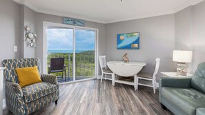 A room with a dining table, two chairs, a sofa, and a view of the ocean. - Sea View and Sunrise Ocean Pointe 2412 2BA/2BR (Tavernier)
