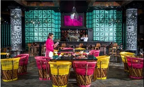 Ein Restaurantinneres mit Korbstühlen, einer Bar und dekorativen Wandverkleidungen.