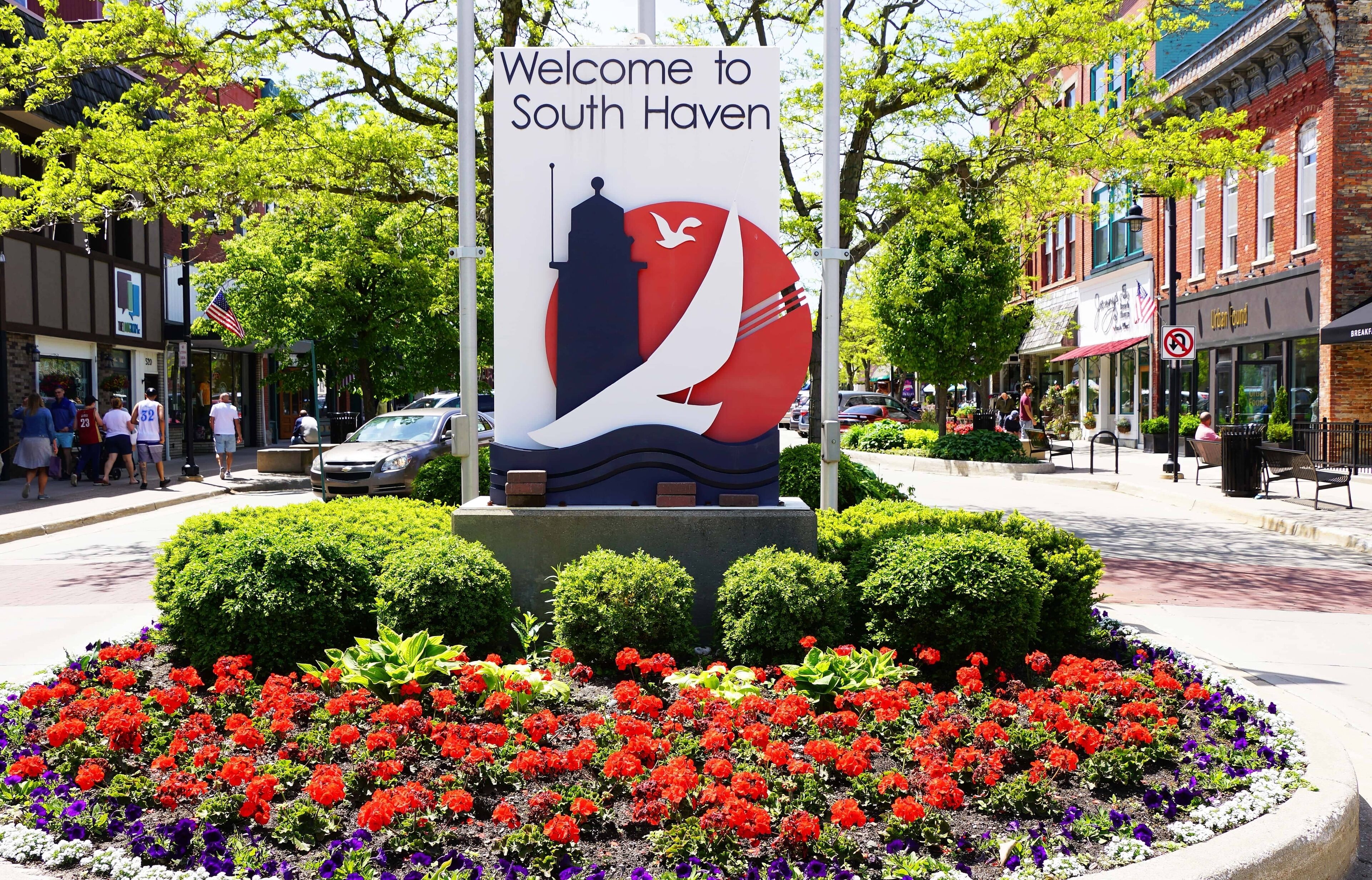 A welcome sign for South Haven with a silhouette of a lighthouse, a bird, and a red and white circular design.
