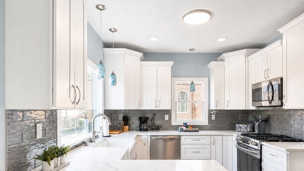 A modern kitchen with white cabinetry, a marble countertop, a stainless steel stove, and a window with a view. - New Remodel with Hot Tub 3 blocks from Beach, 1 block to Town, & Game Room! (South Haven)
