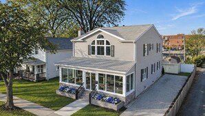 A two-story house with a covered porch, a garage, and a small yard. - New Remodel with Hot Tub 3 blocks from Beach, 1 block to Town, & Game Room! (South Haven)