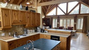 A spacious kitchen with wooden cabinets, a large island with a sink, and a dining area with a view of the outdoors. - NEW LISTING: Large Creemore farmhouse on 50 acres with Tennis and Pool (Honeywood)
