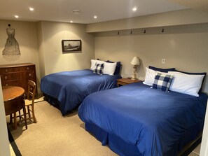 A hotel room with two beds, a wooden dresser, a chair, and a lamp.