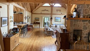 A spacious wooden interior with a kitchen, dining area, and living room, featuring exposed beams and stone accents. - NEW LISTING: Large Creemore farmhouse on 50 acres with Tennis and Pool (Honeywood)