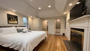Een slaapkamer met een groot bed, een open haard en een inloopkast.