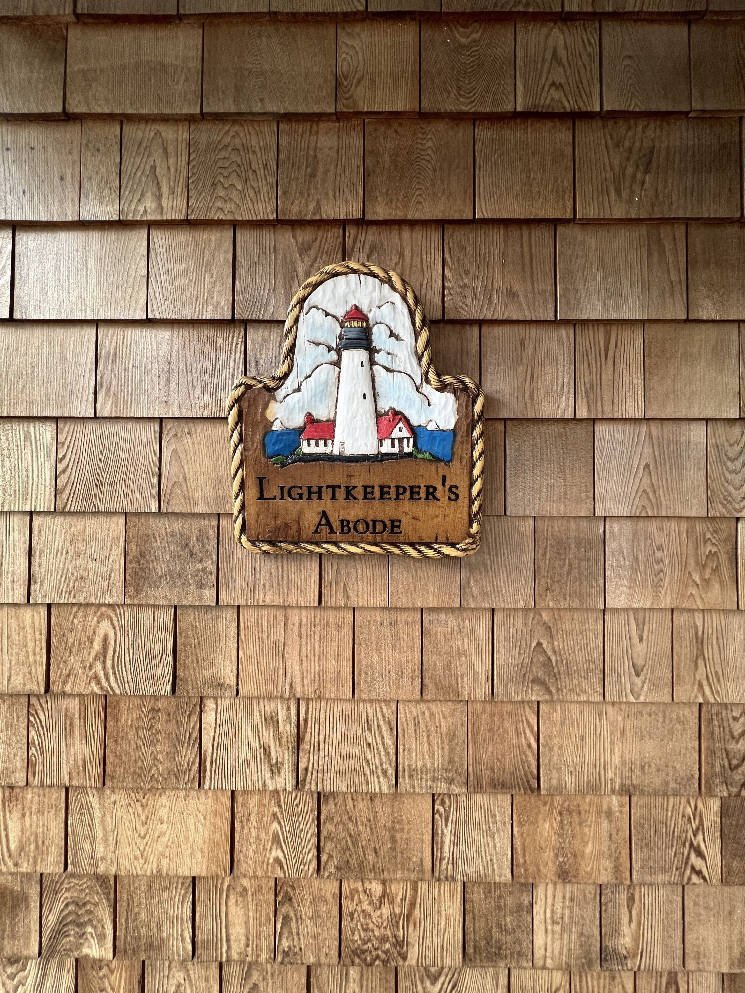 Un muro di legno con un cartello che riporta la scritta 'Lightkeeper's Abode'.