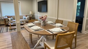 Een eethoek met een houten tafel gedekt voor zes personen, omringd door rieten stoelen met kussens.