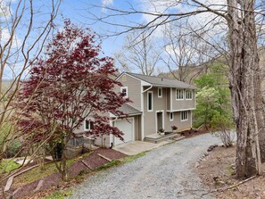 A two-story house with a gravel driveway and a wooden deck.
