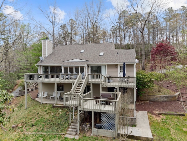A two-story house with a deck, outdoor seating, and a staircase leading to the upper level.