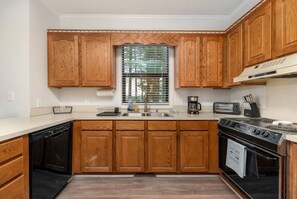 Kitchen area with a dishwasher, stove, and window with blinds.