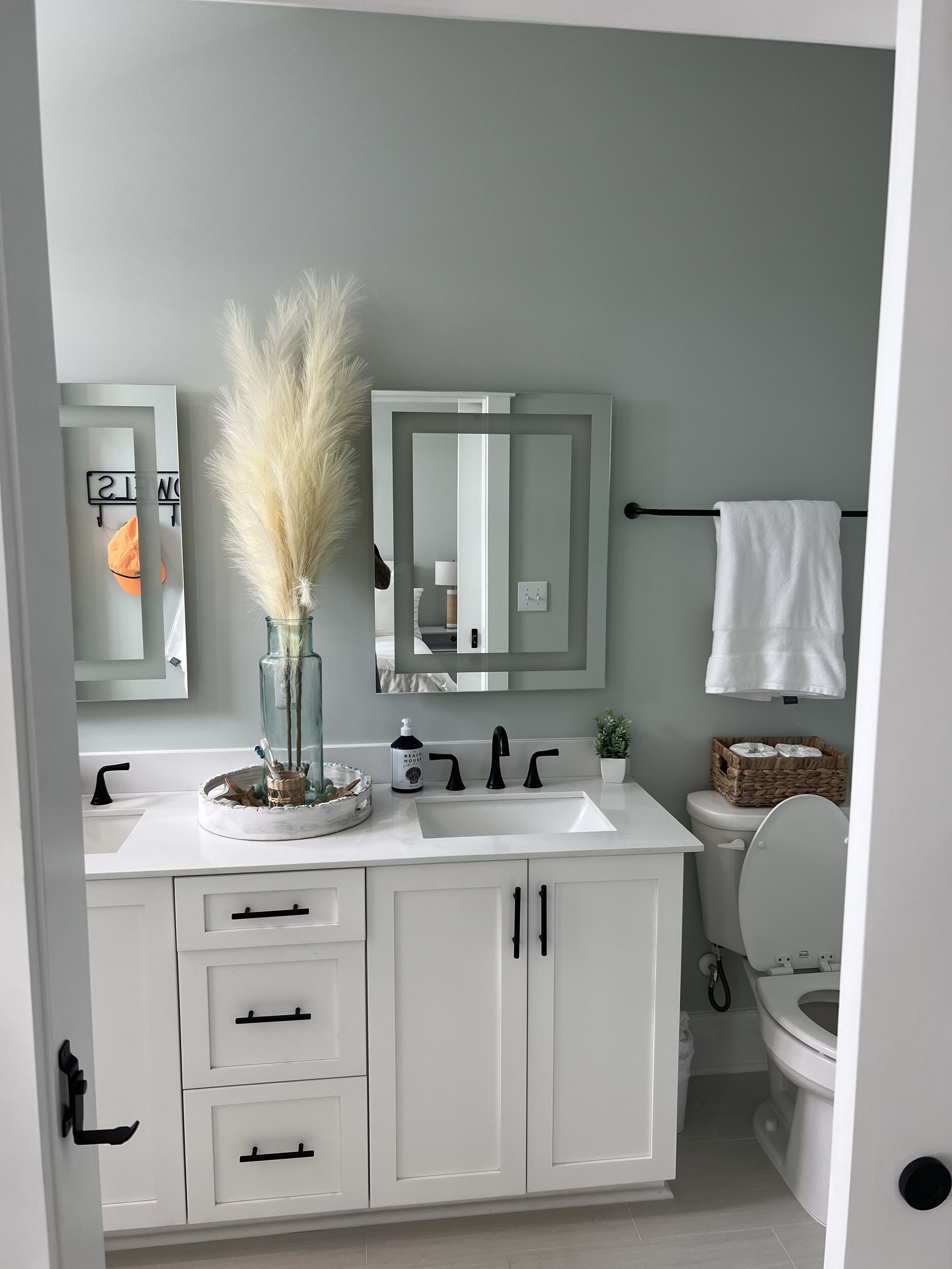 A modern bathroom with a white vanity, a large mirror, and a toilet.