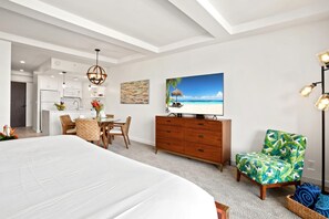 Une chambre à coucher avec un grand lit, une commode en bois, une table à manger avec des chaises et un téléviseur posé sur un meuble.